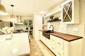 A kitchen with white cabinets, a wooden countertop, and a hanging light fixture. - Acadian Dreams- Entire home next to Acadia (Mount Desert)