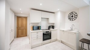 A modern kitchen with white cabinetry, a built-in oven, a microwave, and a coffee maker. - The Vault, Southwold (Southwold)