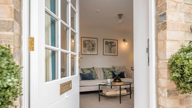 A doorway leading to a living area with a sofa, a coffee table, and two wall-mounted light fixtures. - The Vault, Southwold (Southwold)