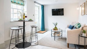 A modern living room with a sofa, a coffee table, and a dining area with a table and stools. - The Vault, Southwold (Southwold)
