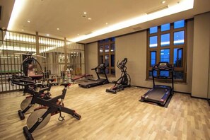 A gym with various exercise equipment, large windows, and a wooden floor. - Lutang Hot Spring Resort (Mianzhu)