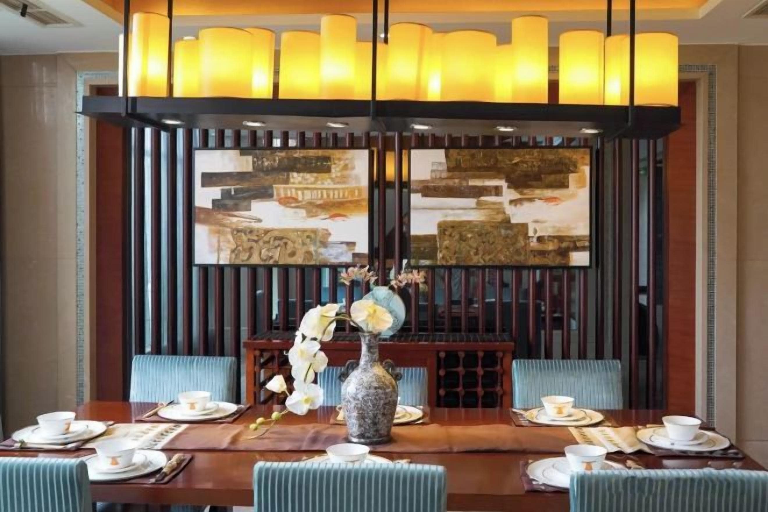 A dining area with a long table, chairs, and a vase with flowers.