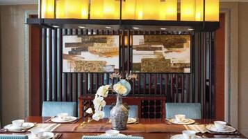 A dining area with a long table, chairs, and a vase with flowers.