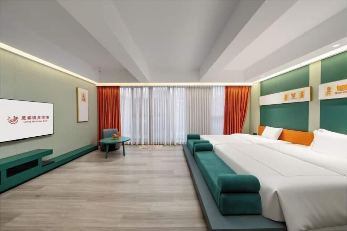 A modern hotel room with a bed, a seating area, and a television.