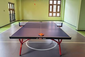 Una mesa de ping pong con una red en el centro, patas rojas y un logotipo en la parte frontal.