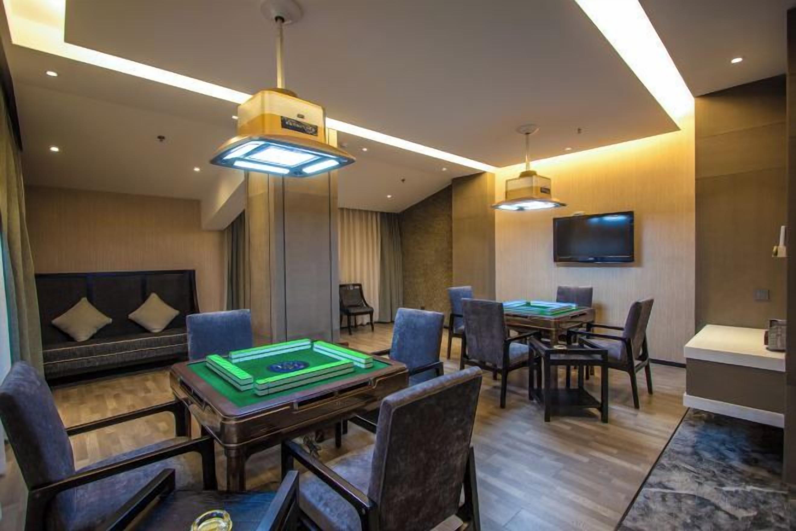 A hotel room with a billiards table, seating area, and a flat-screen TV.