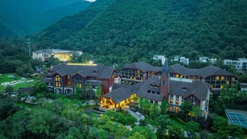 Un hôtel composé de plusieurs bâtiments, entouré d’une végétation luxuriante et de montagnes.