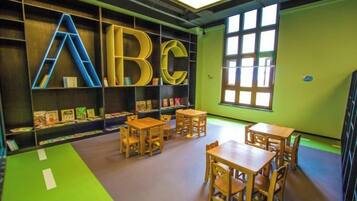 A children's library with alphabet shelves, tables, and chairs.