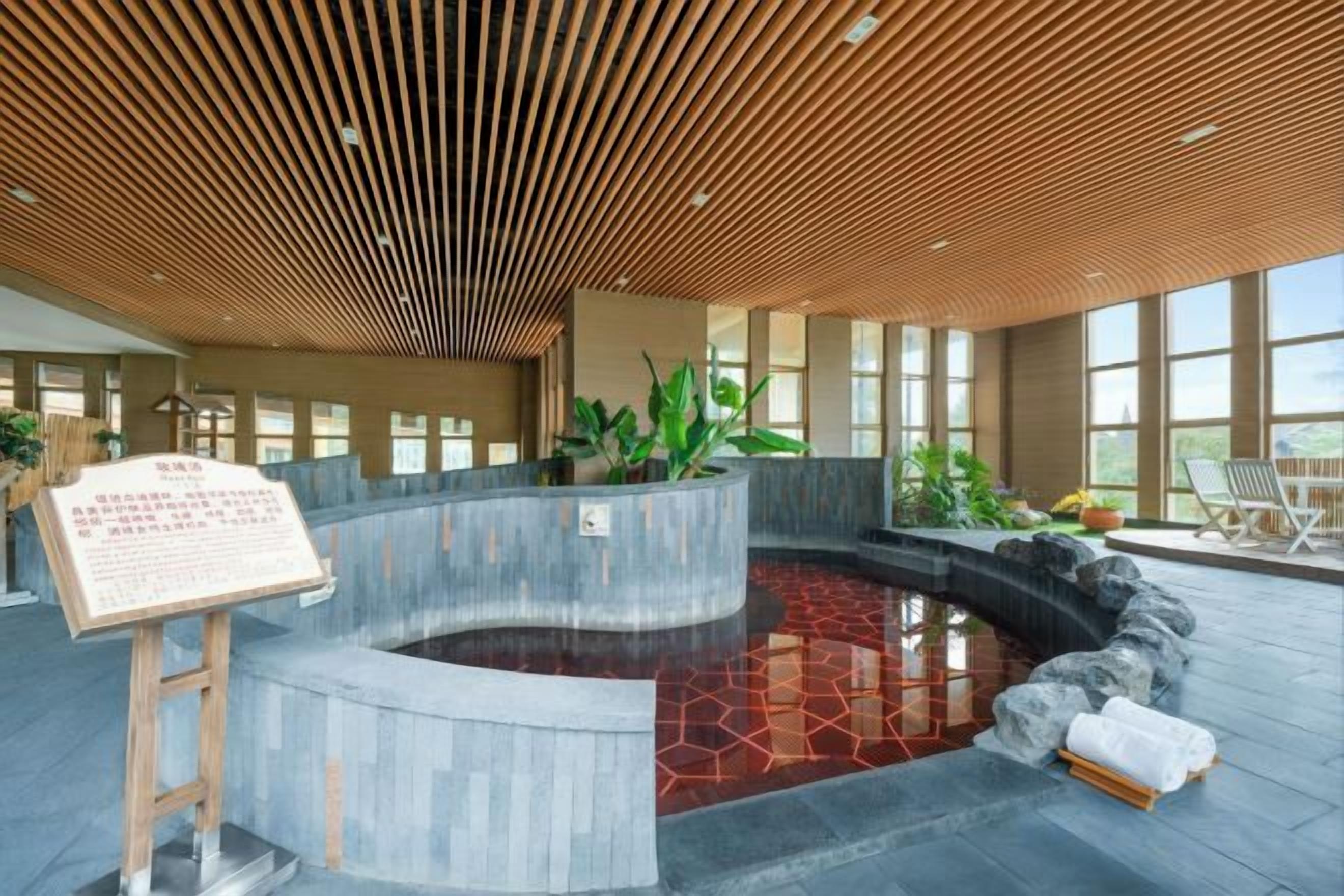 A spa area with a hot tub, wooden ceiling, and large windows.