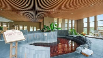 A spa area with a hot tub, wooden ceiling, and large windows.
