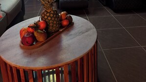Een massageruimte met twee massagestoelen, een houten tafel met fruit, en een decoratieve wand met een ronde spiegel.