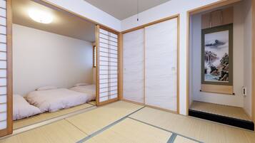 Een traditionele Japanse kamer met tatami vloeren, een futonbed, schuifdeuren en een lijstwerk met kunst.