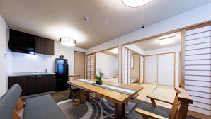 Een moderne keuken met donkere kastjes, een koelkast en een eethoek met een houten tafel en stoelen.