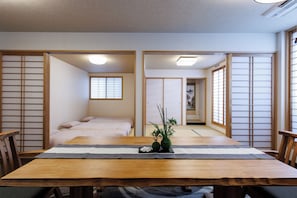Una habitación japonesa tradicional con suelo de tatami, una mesa de madera con camino de mesa y puertas correderas shoji.
