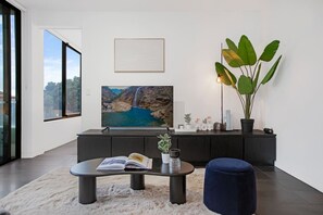 A modern living room with a large window, a television, a coffee table, a sofa, and a potted plant. - 2BR Surry Hills | Free Parking, Walk to Central (Surry Hills)