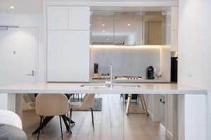 A modern kitchen with a large island, a built-in oven, and a coffee machine. - Luxury CBD 3BR | Pool, Fireworks Views (Haymarket)