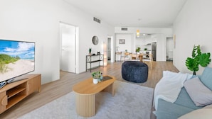Een moderne woonkamer met een flatscreen televisie, een houten salontafel en een bank.