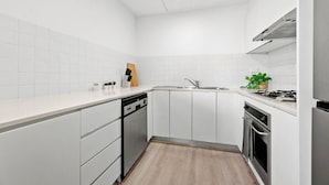 Een moderne keuken met witte kasten, een vaatwasser, een spoelbak, een fornuis en een magnetron.