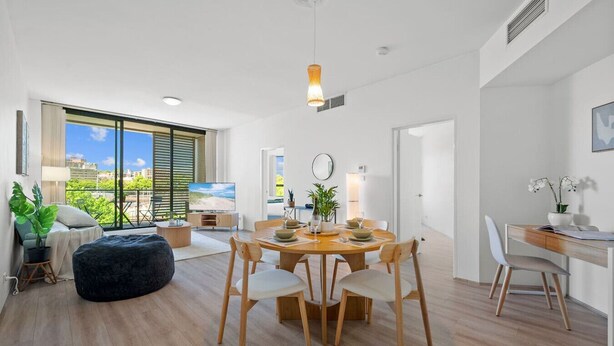 Een moderne woonkamer met een eetgedeelte, grote ramen en uitzicht op de stad.