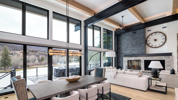 A spacious living area with a fireplace, large windows, and a dining table. - Luxury 4 bd home on Rollingstone Ranch Golf Course (Steamboat Springs)