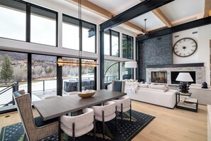 A spacious living area with a fireplace, large windows, and a dining table. - Luxury 4 bd home on Rollingstone Ranch Golf Course (Steamboat Springs)