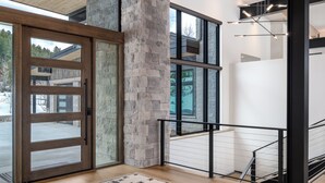 A modern interior with a wooden ceiling, a large rug, a stone pillar, and a view through a glass door. - Luxury 4 bd home on Rollingstone Ranch Golf Course (Steamboat Springs)