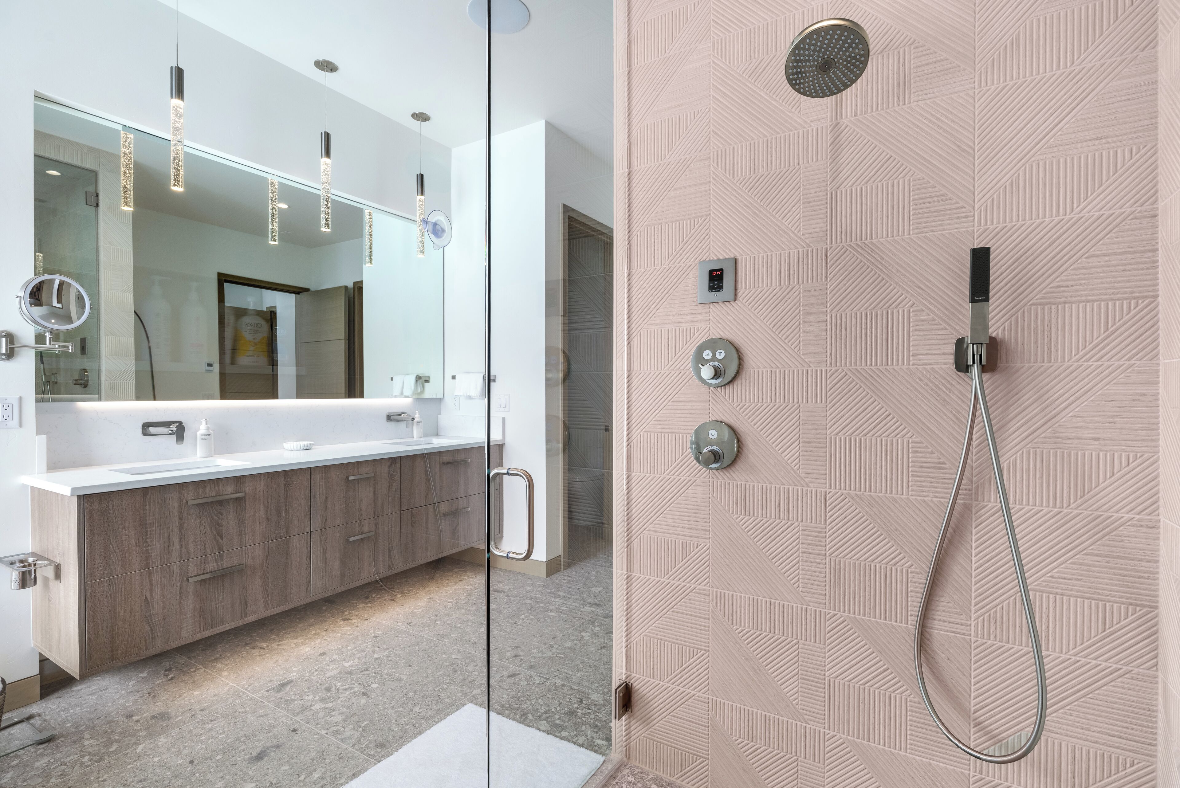 Une salle de bain moderne dotée d’une douche à parois de verre, d’un grand miroir et d’un meuble-lavabo avec un évier et un placard.