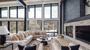 A spacious living room with a large sofa, a fireplace, and a view of the outdoors. - Luxury 4 bd home on Rollingstone Ranch Golf Course (Steamboat Springs)