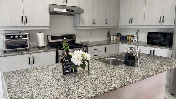 A modern kitchen with granite countertops, stainless steel appliances, and light wood cabinetry. - 4 BR Spacious Home in Barrie (Barrie)