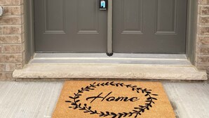 A double door with frosted glass panels, a keypad lock, and a doormat with 'Home' written on it. - 4 BR Spacious Home in Barrie (Barrie)