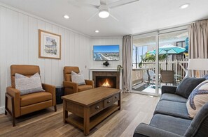 Ein Wohnzimmer mit Kamin, zwei Sesseln, einer Couch und einem Fernseher.