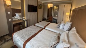 A hotel room with two beds, a desk, a chair, a TV, and a mirror.