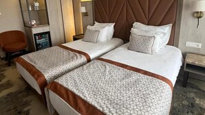 A hotel room with two beds, a minibar, a seating area, and a mirror.