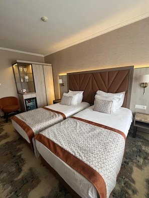 A hotel room with two beds, a minibar, a seating area, and a mirror.