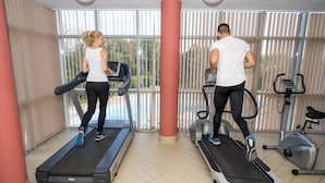 Two people exercising on treadmills in a room with large windows and exercise equipment. - Spa Hotel Hissar (Hisarja)