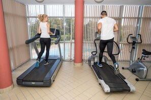 Two people exercising on treadmills in a room with large windows and exercise equipment. - Spa Hotel Hissar (Hisarja)