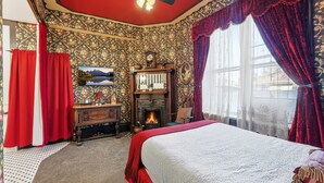 A bedroom with a bed, a fireplace, and a large window with curtains.