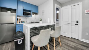 Eine moderne Küche mit blauen Schränken, einem weißen Kühlschrank und einer schwarzen Mülltonne.