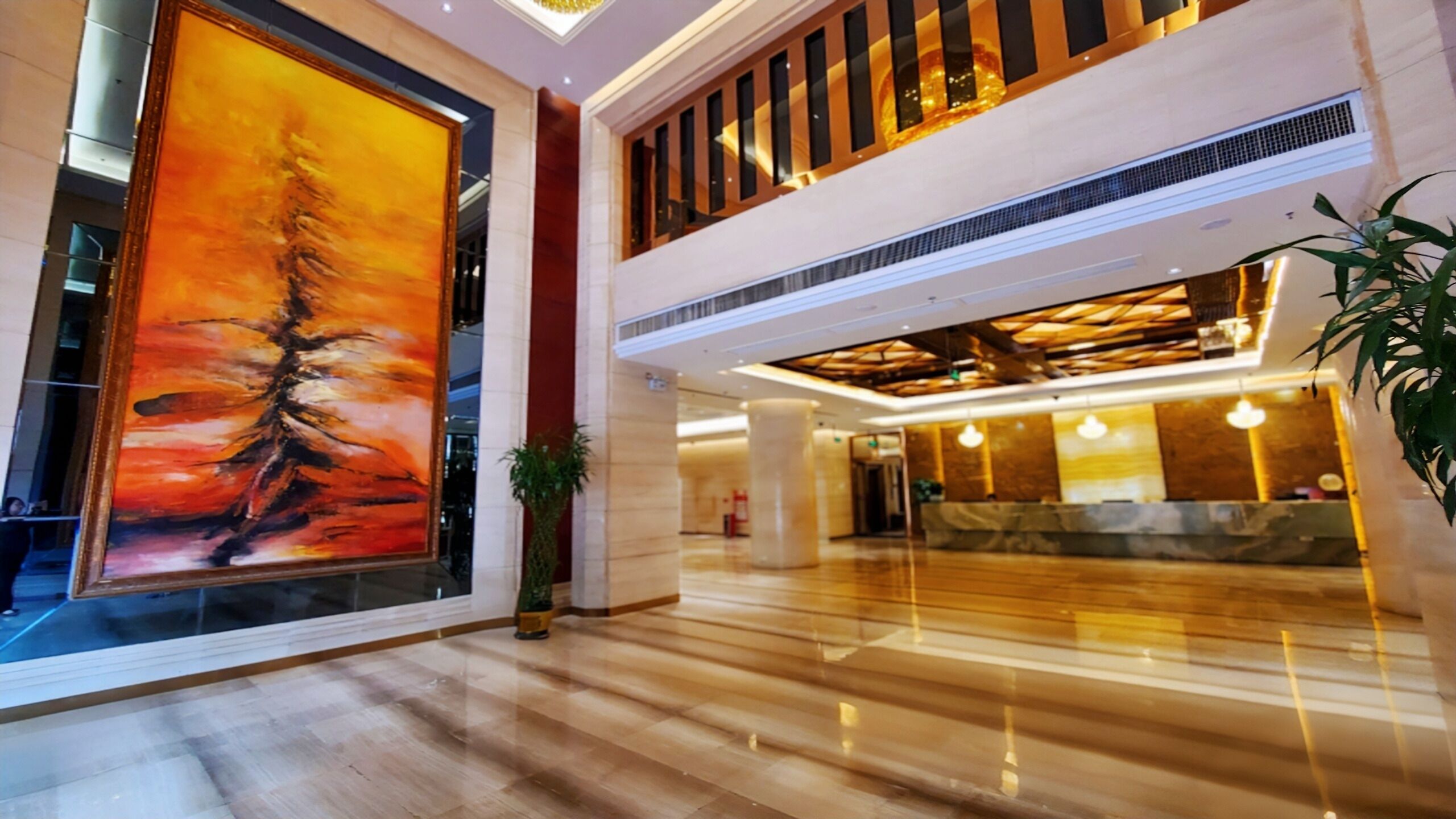 Een ruime lobby met een groot abstract schilderij, een receptiebalie en een hoog plafond met zichtbare balken.