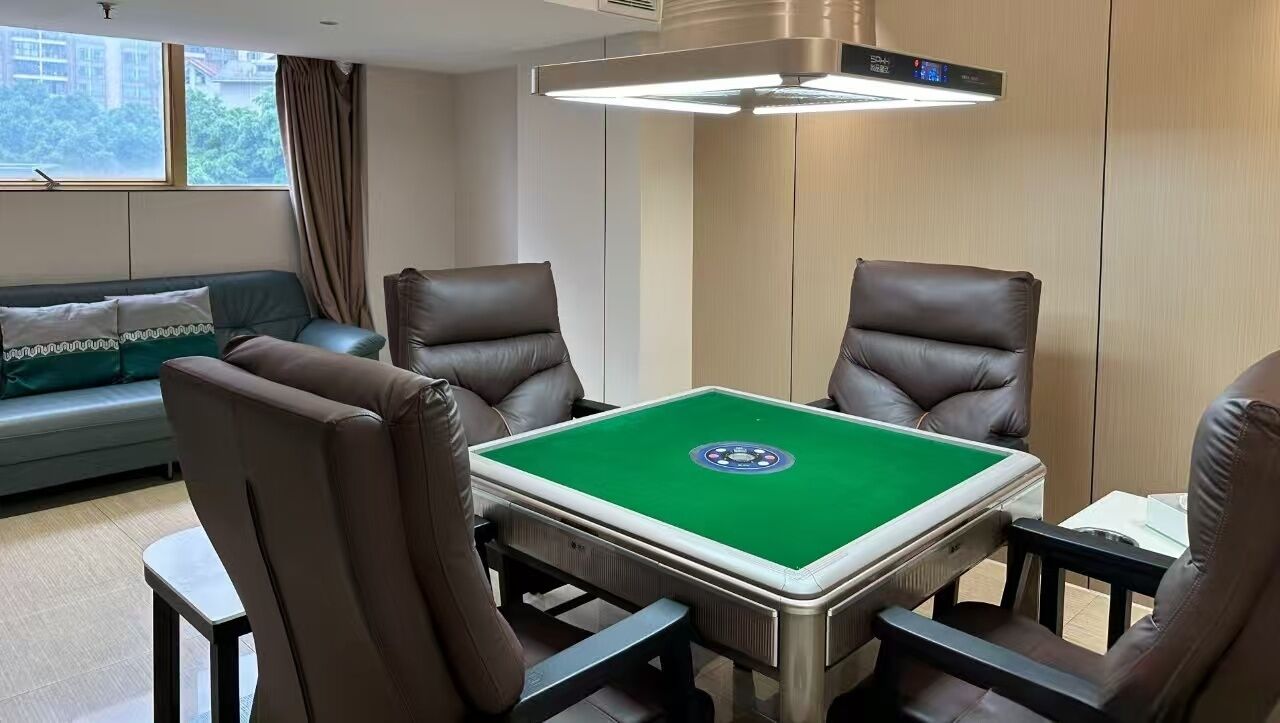 Una habitación con mesa de billar, cuatro sillones de cuero, un sofá y un ventanal con cortinas.