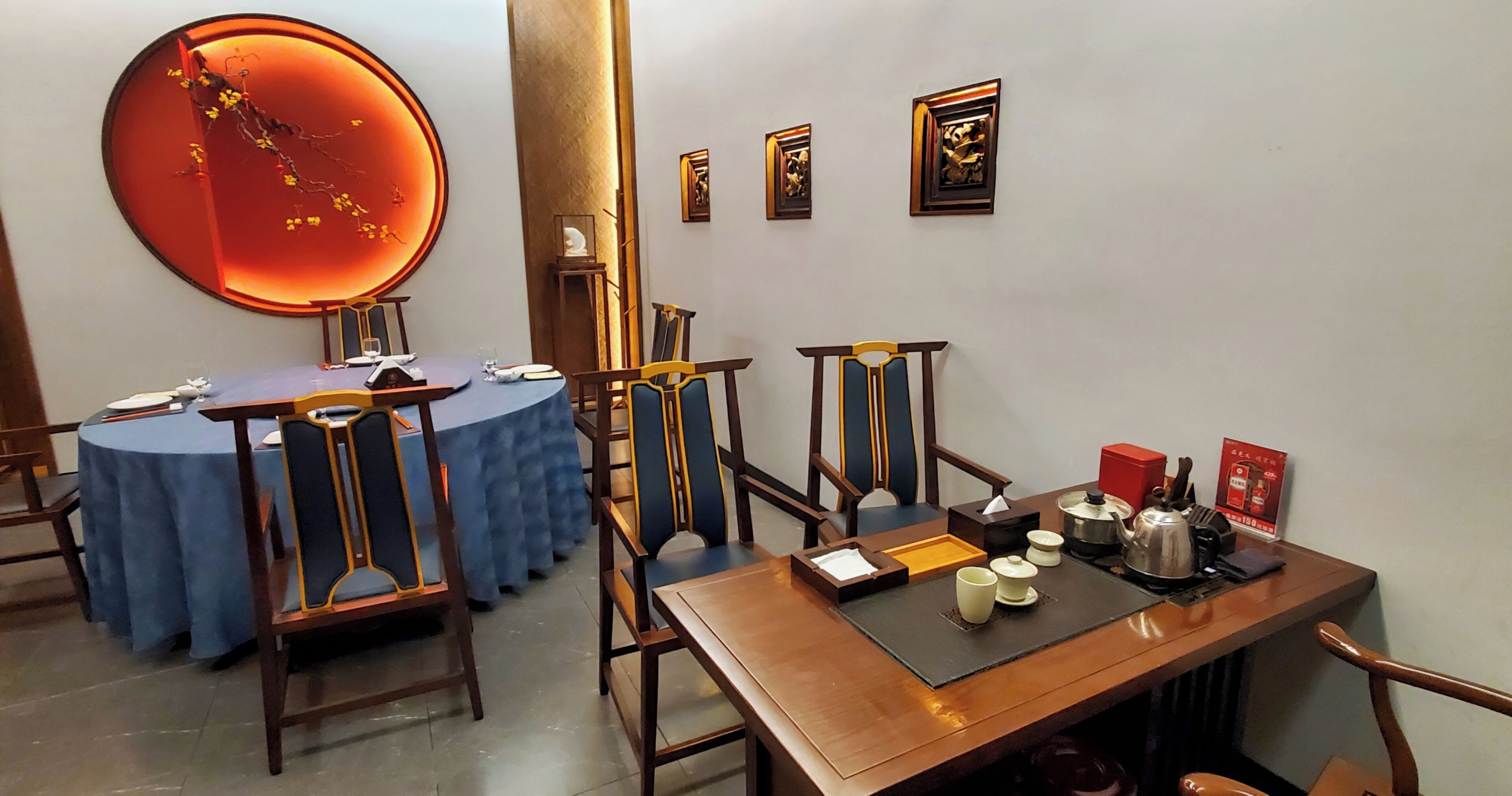 A dining area with round tables, chairs, and a wall-mounted decorative piece.