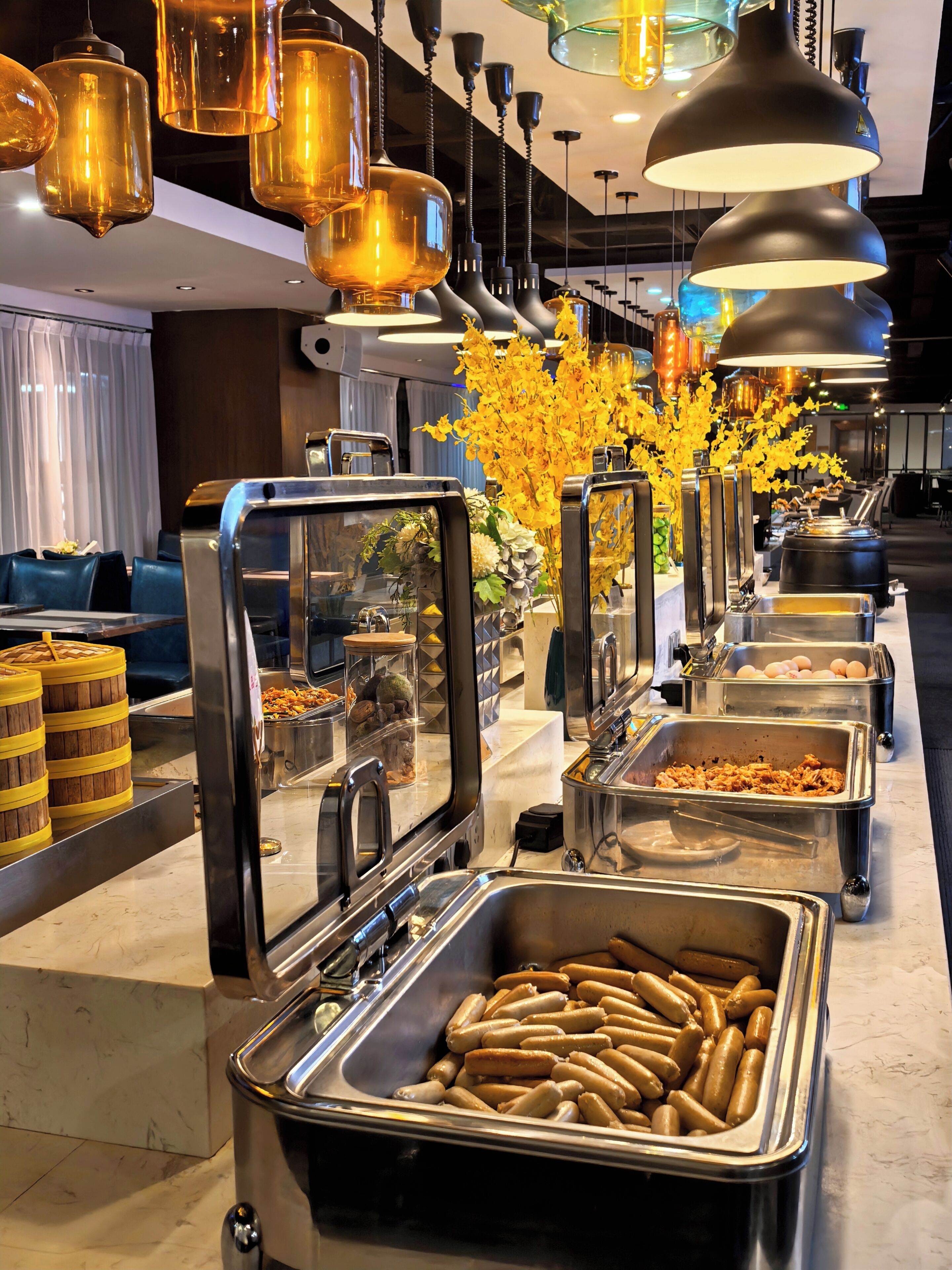 A buffet area with various food options, including sausages and a flower arrangement.