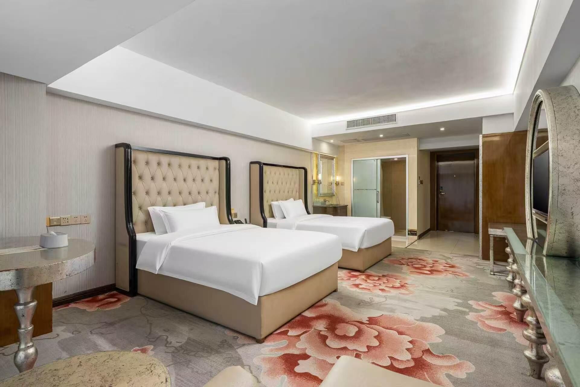 A hotel room with two beds, a bathroom, and a large mirror.
