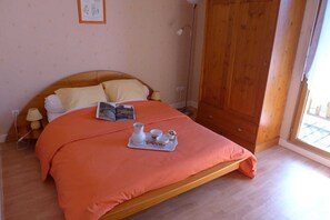 Une chambre à coucher avec un lit, une lampe de chevet, une armoire en bois et une fenêtre.