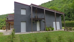 A two-story building with a balcony, a covered porch, and a small garden area. - PASSIFLORE - Froncles (Froncles)