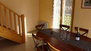 A dining area with a wooden table, chairs, and a bottle of champagne. - PASSIFLORE - Froncles (Froncles)