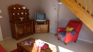 A living room with a wooden cabinet, a television, a red armchair, and a coffee table. - PASSIFLORE - Froncles (Froncles)