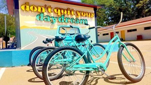 A turquoise bicycle parked in front of a building with a mural that reads 'don't quit your daydream.' - Boutique Hotel | Double Queen | Game Day (Starkville)