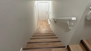 A staircase with wooden steps leading to a white door at the top. - Cozy  Nook (Saskatoon)