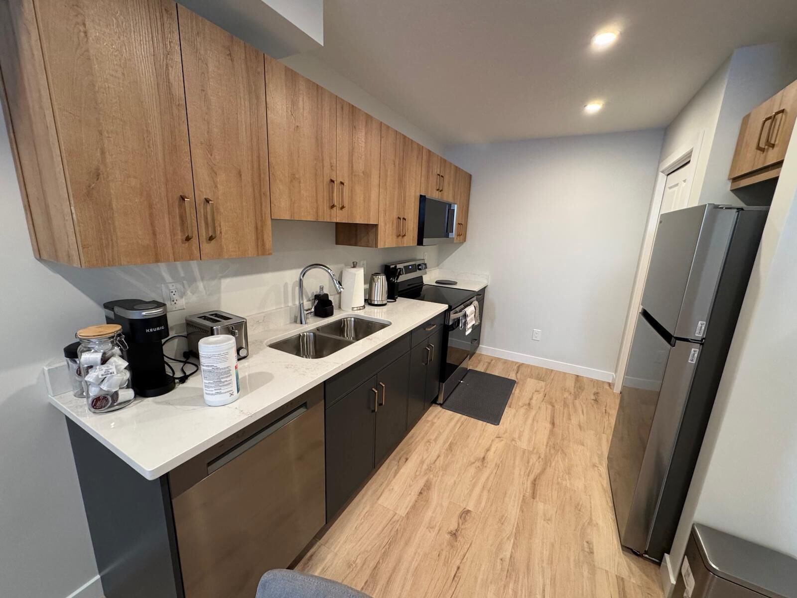 Una cocina compacta con armarios de madera, un lavamanos doble, una estufa y un refrigerador.